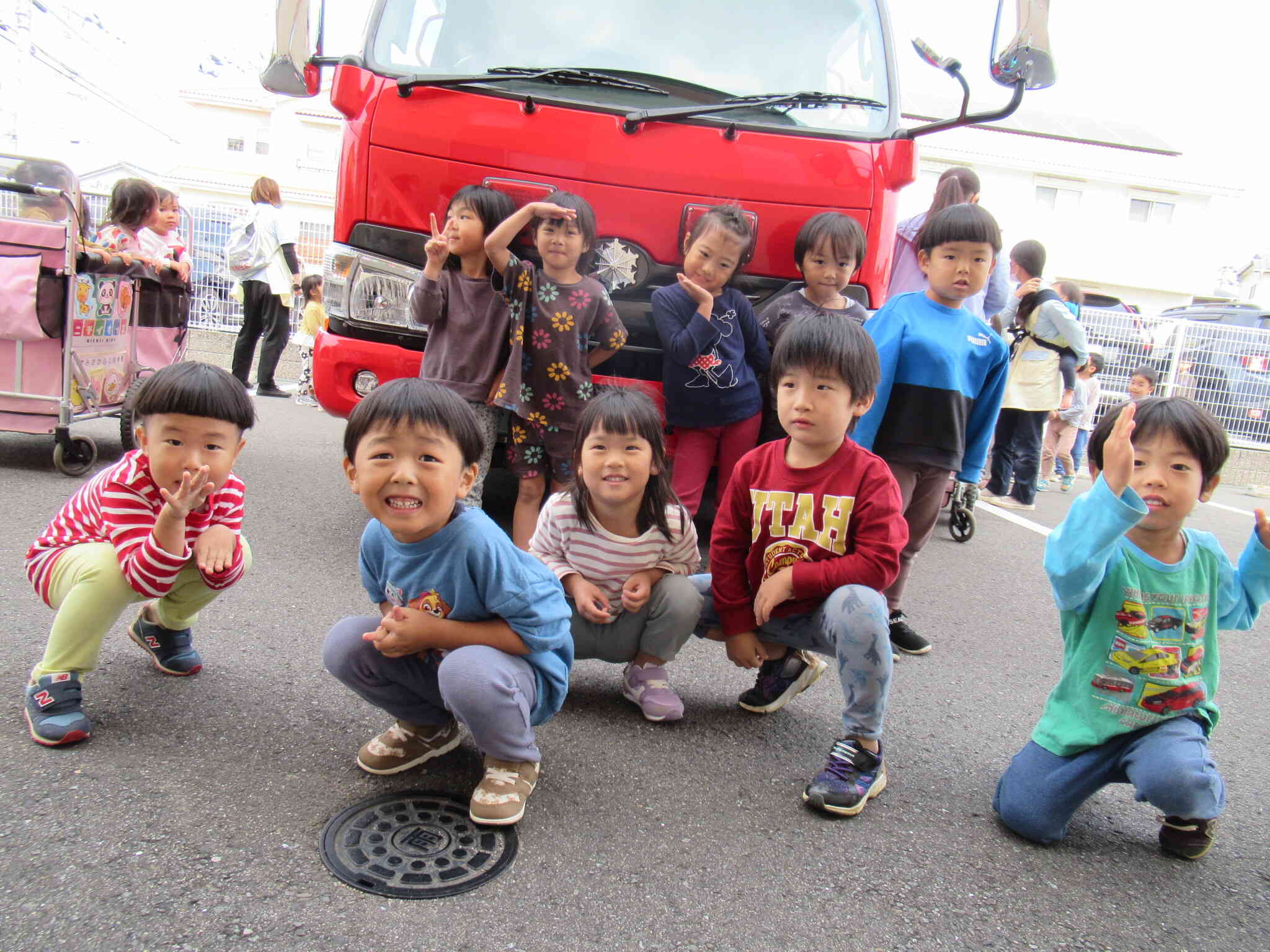 消防車と一緒に記念撮影！やったー！と大喜びの子どもたち♡「みんなこっち向いて～♪」元気いっぱいの子どもたち、ポーズも決まっているね！