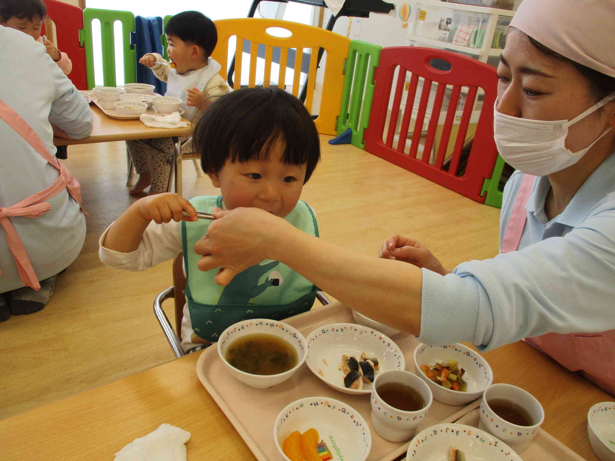 保育者に手伝ってもらいながら自分で食べる練習しているよ。