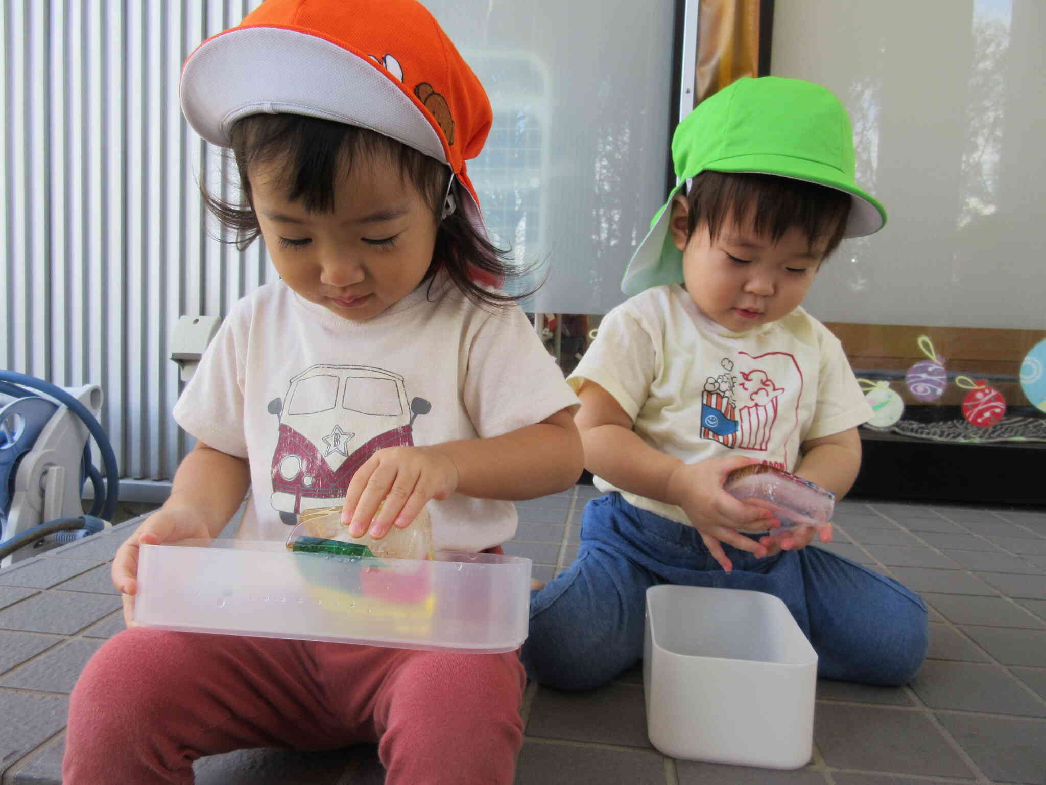 カラーセロハンの色氷を持って最後の水遊び(1、2歳児)