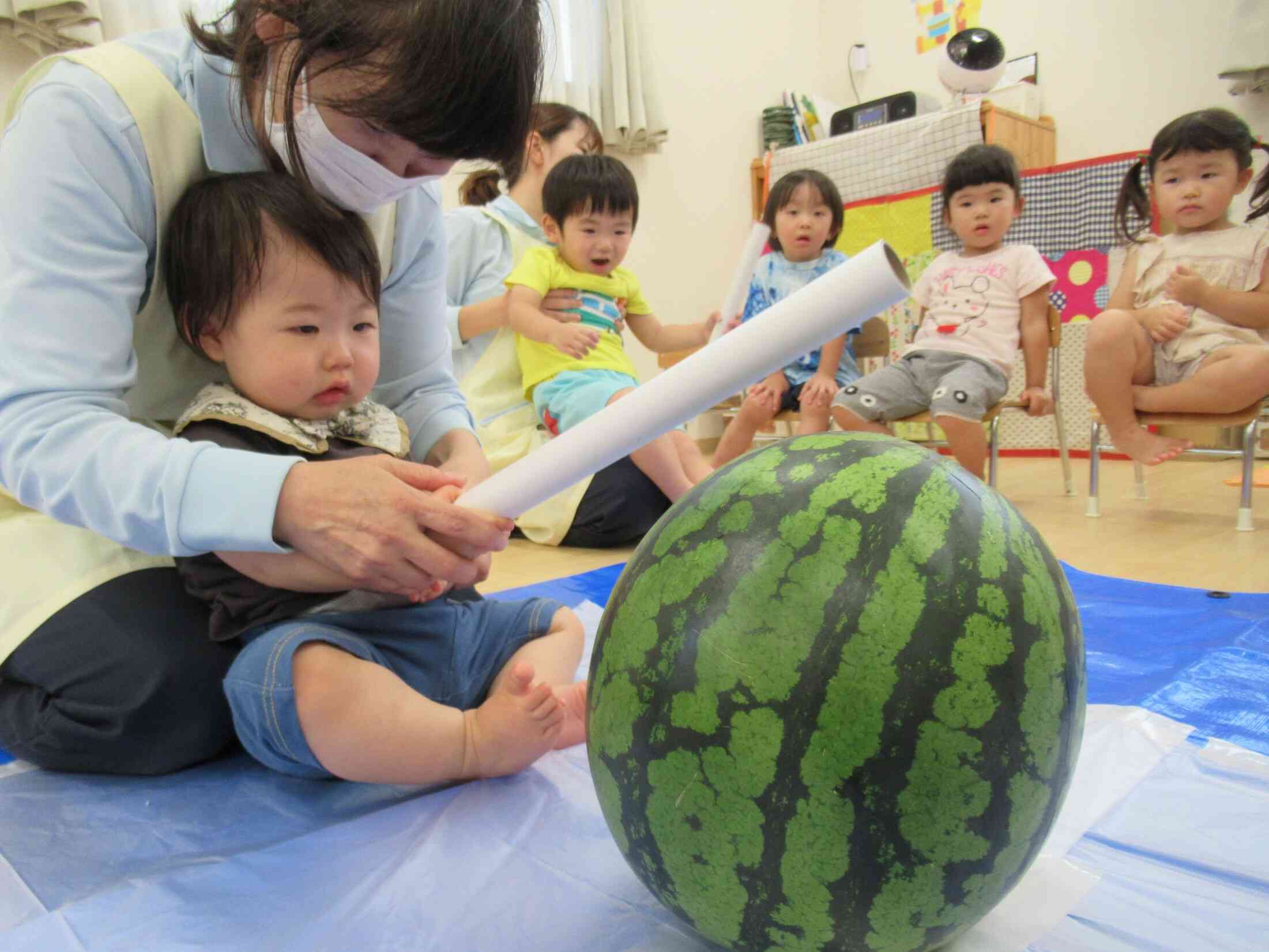 先生と一緒に「えい！」　0歳児さんよりも大きなスイカに見えちゃいますね