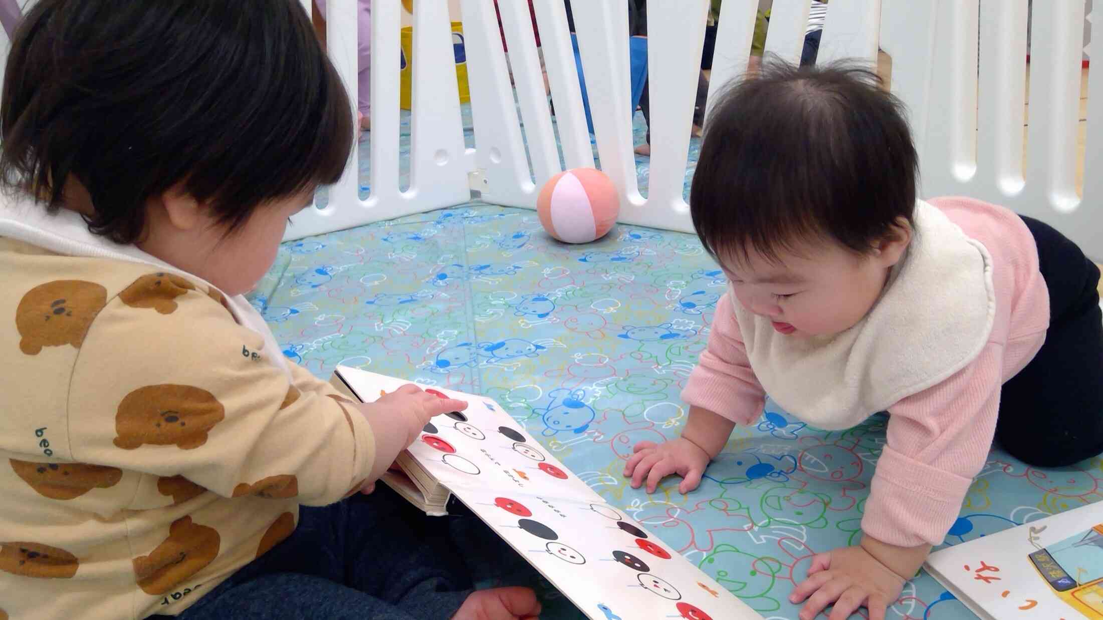 0歳児クラスでの一コマです！ちょっぴり大きな月齢の子がまるで絵本を読んであげているようですね♡