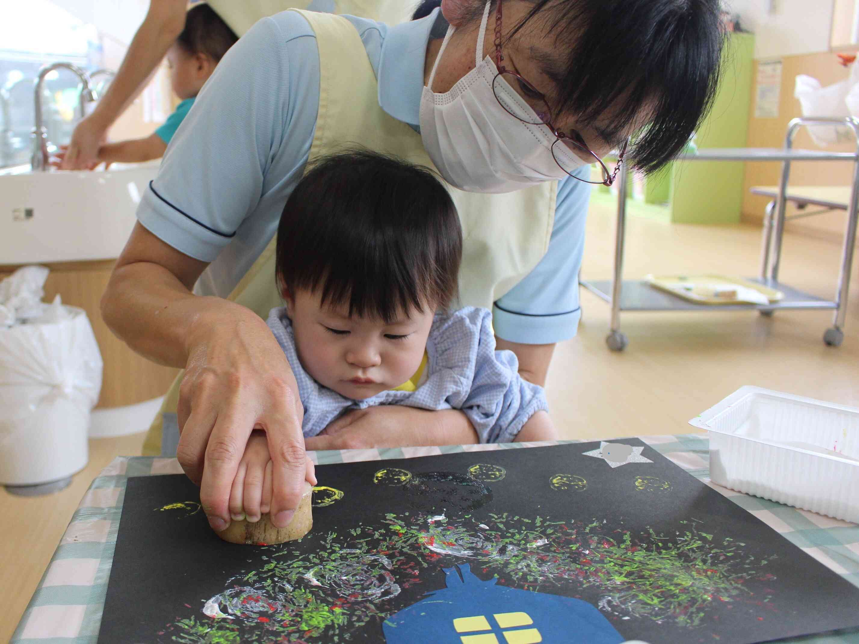 ０歳児のお友達は保育士と一緒にペタペタ、ぺったん。