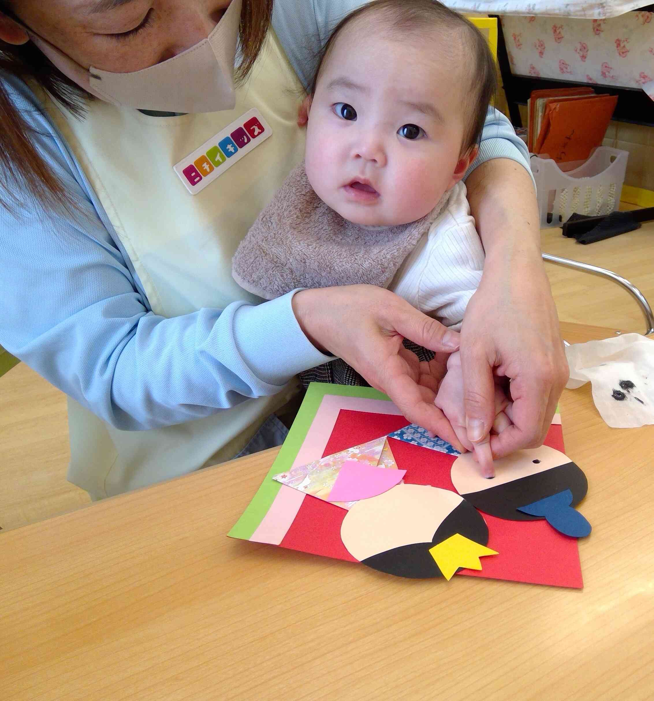 ひよこ組さんも保育士と一緒に指スタンプに挑戦！指に付いたインクに不思議そうな様子が可愛らしかったです。