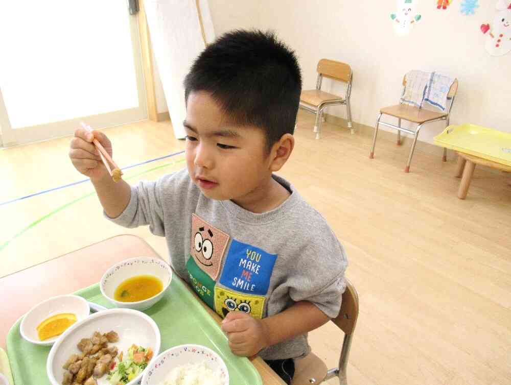 今日の給食は、ご飯、鶏肉と大豆のごま絡め、キャベツのサラダ、カボチャのお味噌汁、オレンジ、ツナサンド（おやつ）でした♪  お箸で上手に大豆を掴んでいます(*^-^*)