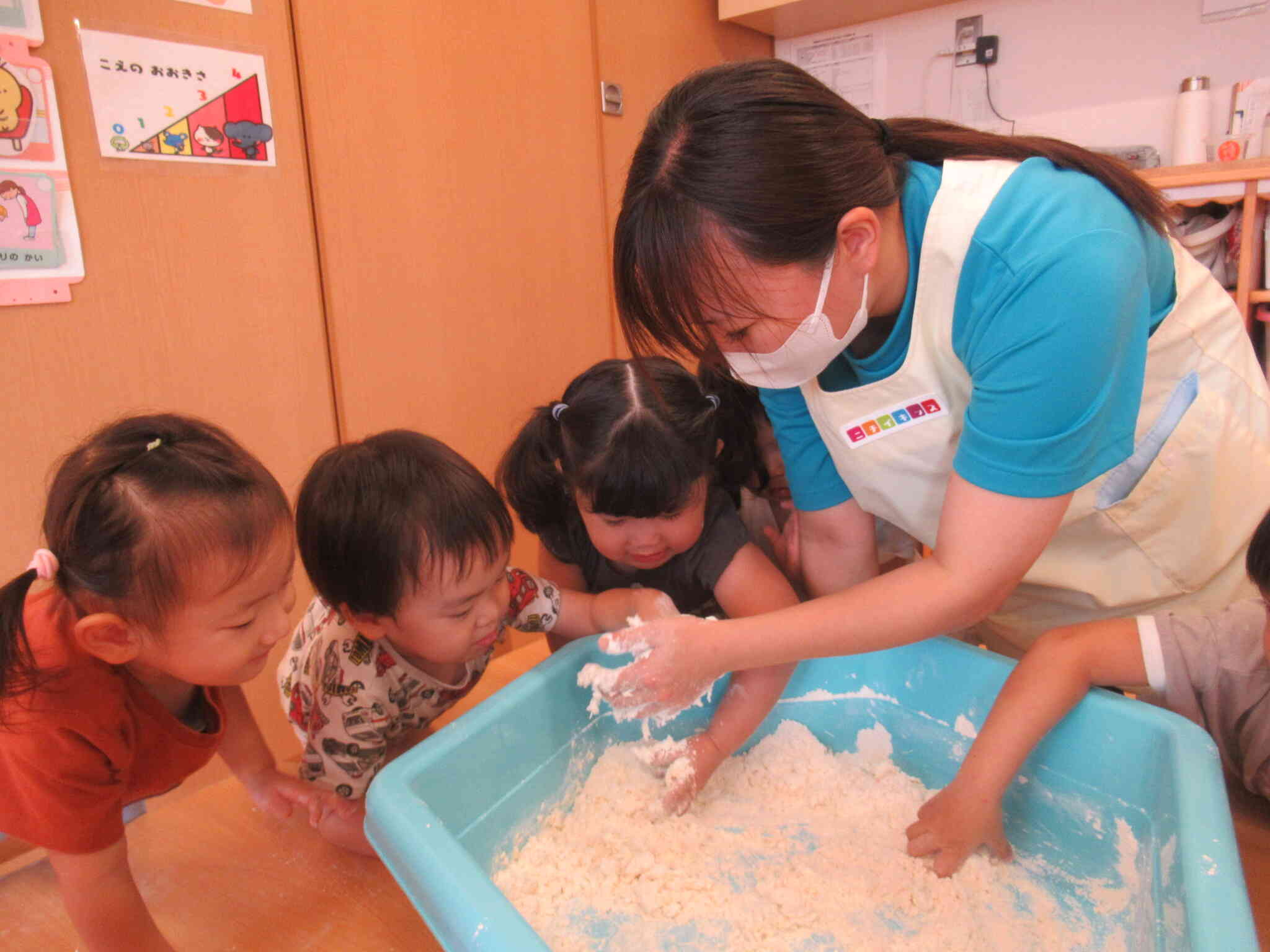 先生の手にくっついている粘土を恐る恐る触ってみる子どもたち