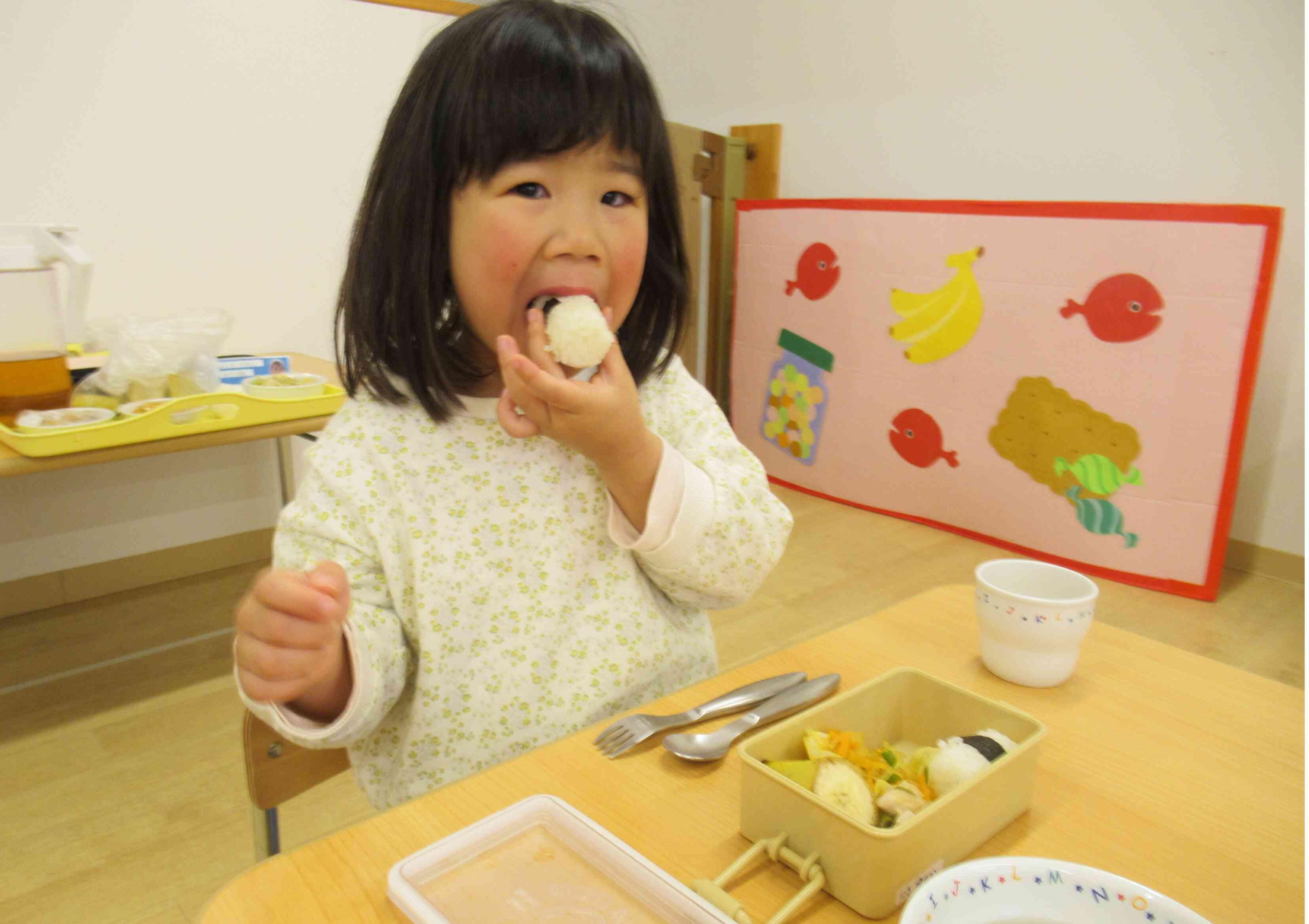 ２回目のお弁当給食です。大きなお口でおにぎりをパクッ！「おいしいね～」